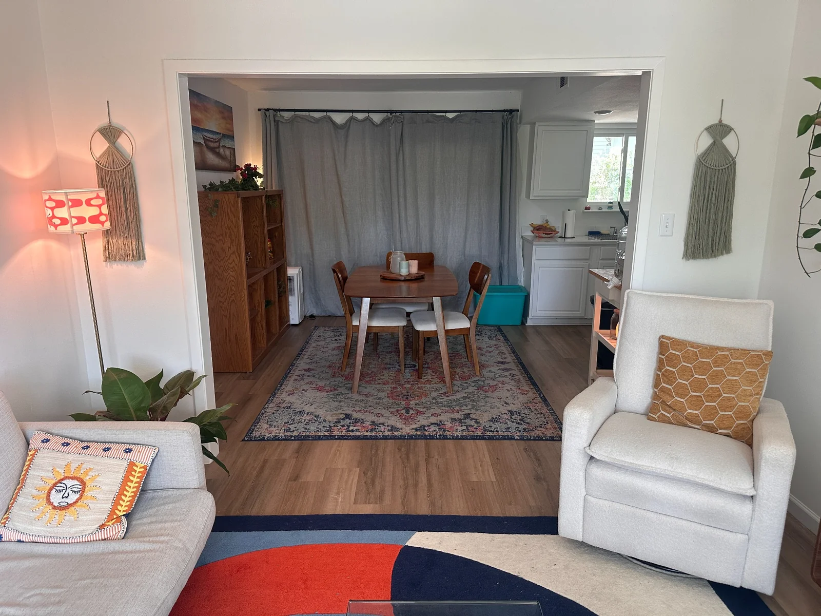Wooden dining table and chairs beside a white kitchen, viewed from the adjoining living room