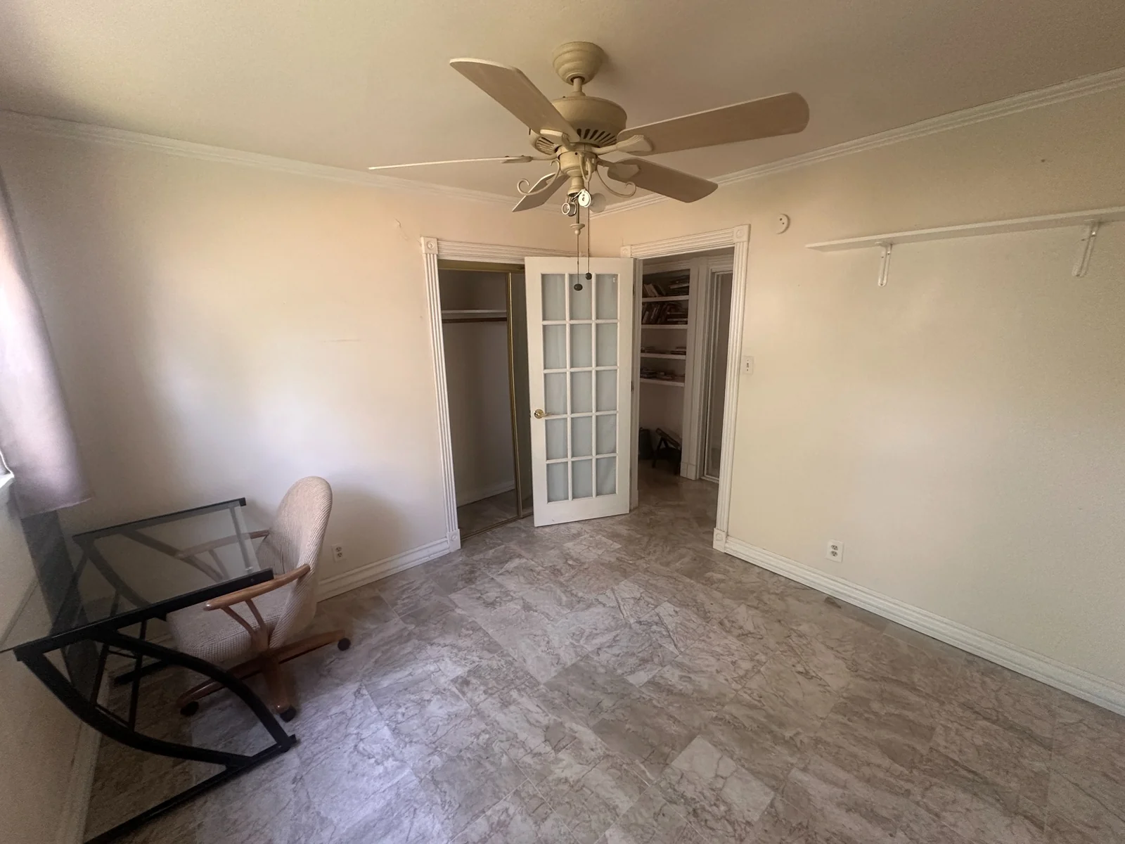 Reverse view of the unfurnished room showing the closet, glass-paneled doorway, and ceiling fan