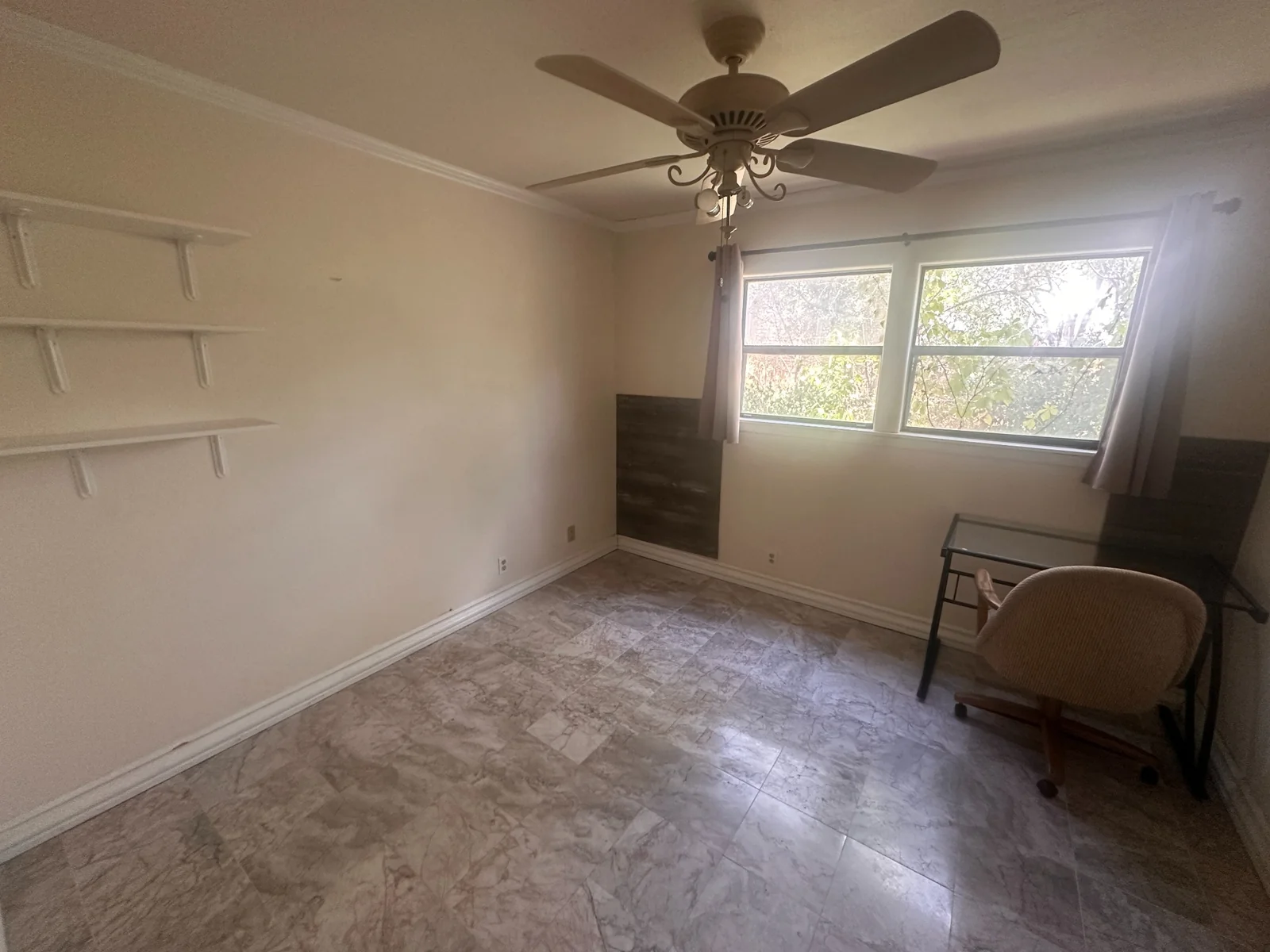 Unfurnished room with wall shelves, a ceiling fan, and a wide window